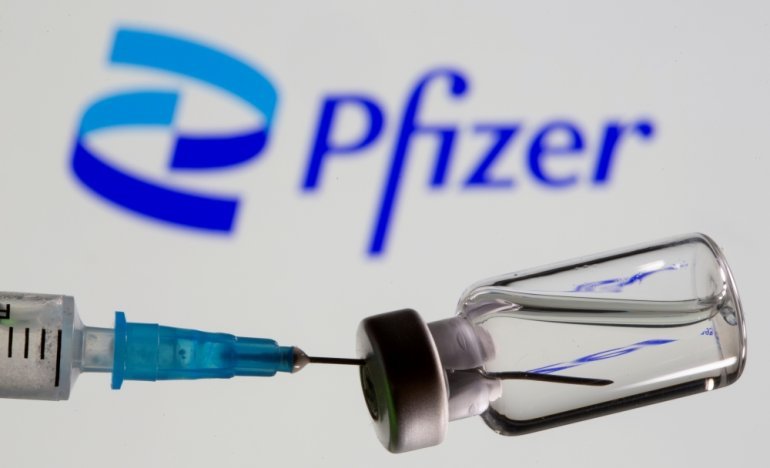 FILE PHOTO: Syringe and vial are seen in front of displayed new Pfizer logo in this illustration taken, June 24, 2021. REUTERS/Dado Ruvic/Illustration
