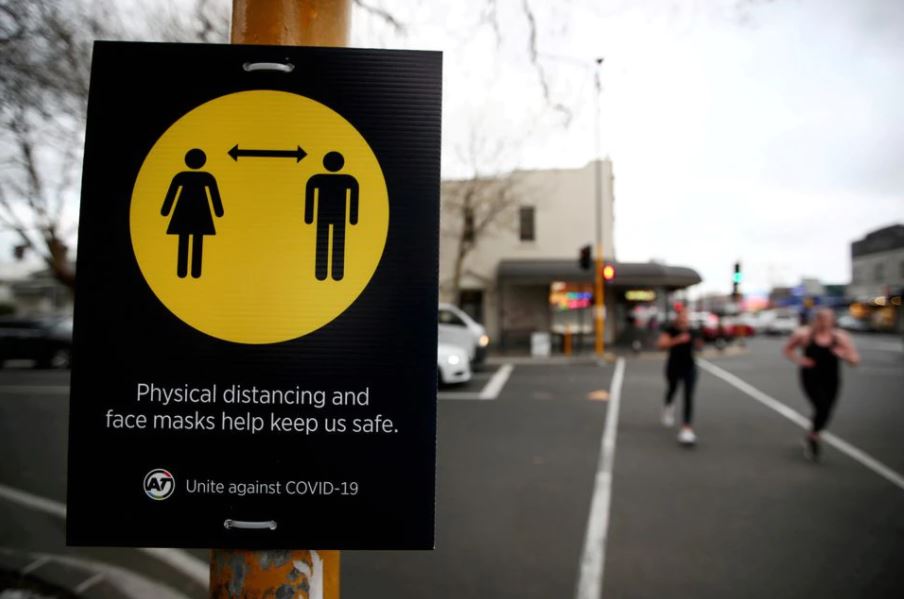 People jog past a social distancing sign on the first day of New Zealand's new coronavirus disease (COVID-19) safety measure that mandates wearing of a mask on public transport, in Auckland, New Zealand, August 31, 2020. REUTERS/Fiona Goodall/File Photo
