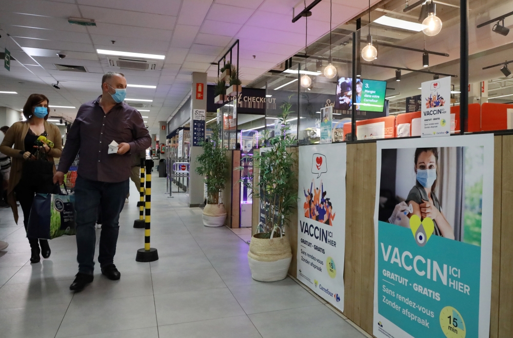 Shoppers, wearing protective face masks, walk past posters for a coronavirus disease (COVID-19) vaccination centre installed inside a supermarket in Brussels, Belgium, August 30, 2021. REUTERS/Bart Biesemans
