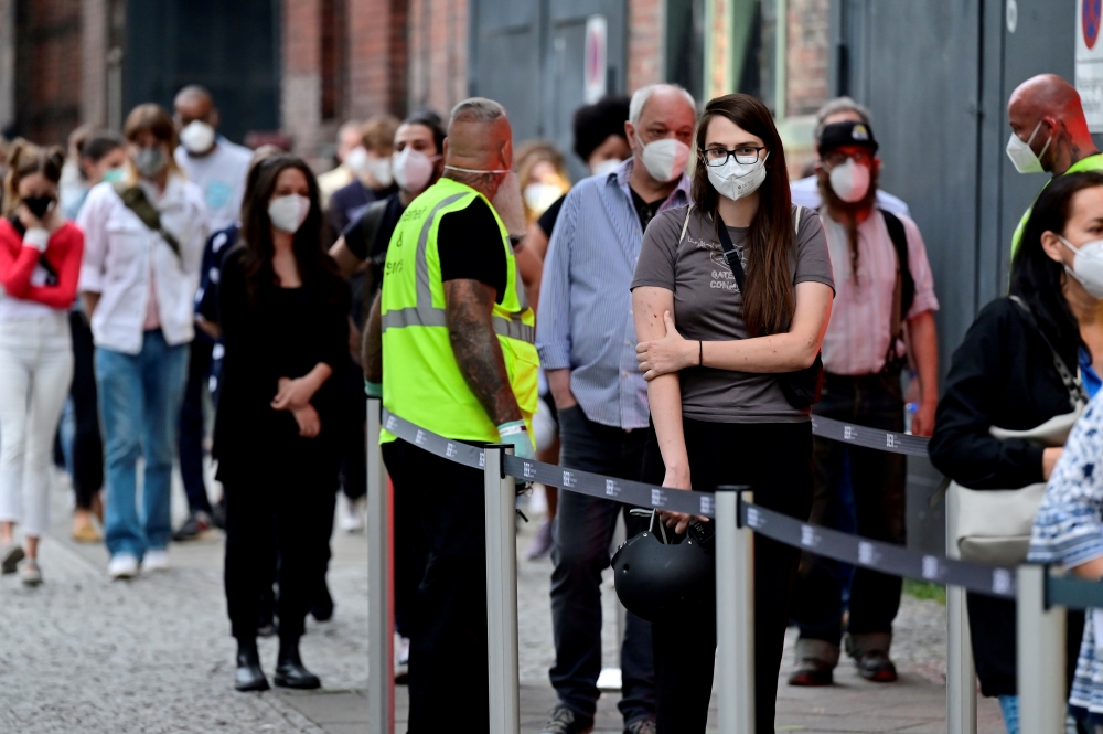 People queue to receive a vaccine against the coronavirus disease (COVID-19), during a night of vaccinations with music, at the Arena Treptow vaccination centre in Berlin, Germany, August 9, 2021. John Macdougall/Pool via REUTERS/File Photo
