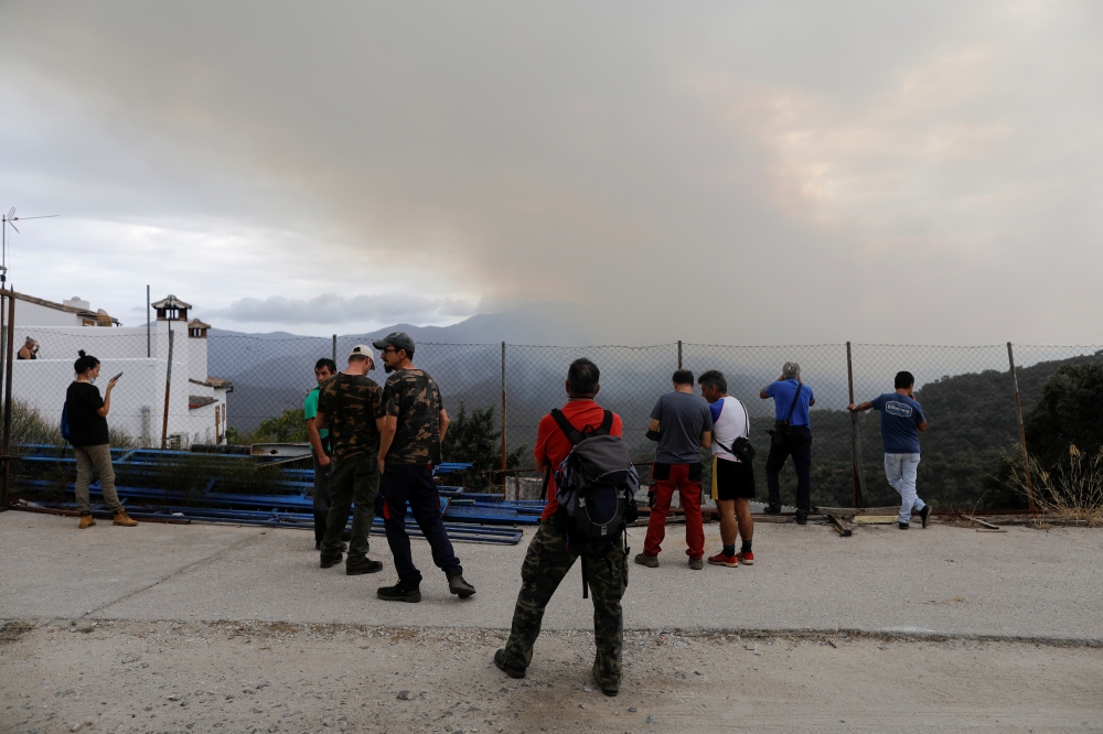 Residents watch a wildfire on Sierra Bermeja mountain after they made a firewall in Benarraba, near Estepona, Spain, September 13, 2021. Reuters/Jon Nazca