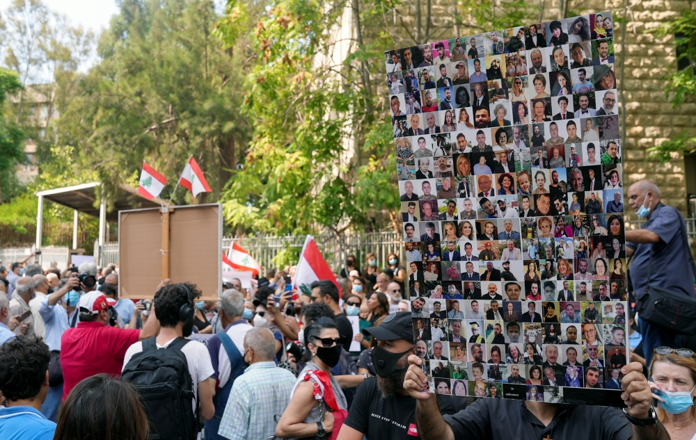 A demonstrator carries pictures of the victims of the 2020 Beirut port blast during a protest in front of the Justice Palace after a probe into the blast was frozen, in Beirut, Lebanon September 29, 2021. REUTERS/Issam Abdallah