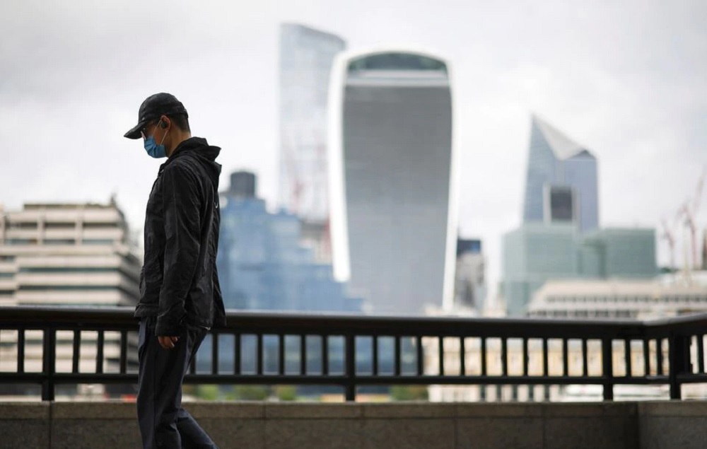 The City of London financial district is seen as a man wearing a protective face mask walks along the River Thames, amid the coronavirus disease (COVID-19) pandemic in London, Britain, July 27, 2021. REUTERS/Henry Nicholls