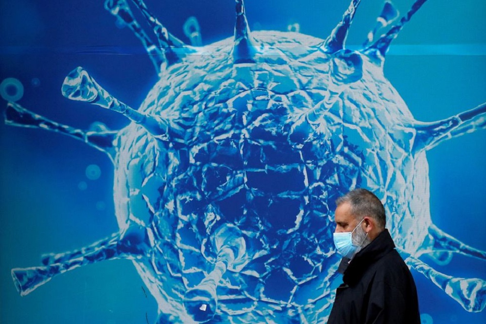 A man wearing a protective face mask walks past an illustration of a virus outside a regional science centre amid the coronavirus disease (COVID-19) outbreak, in Oldham, Britain August 3, 2020. REUTERS/Phil Noble/File Photo
