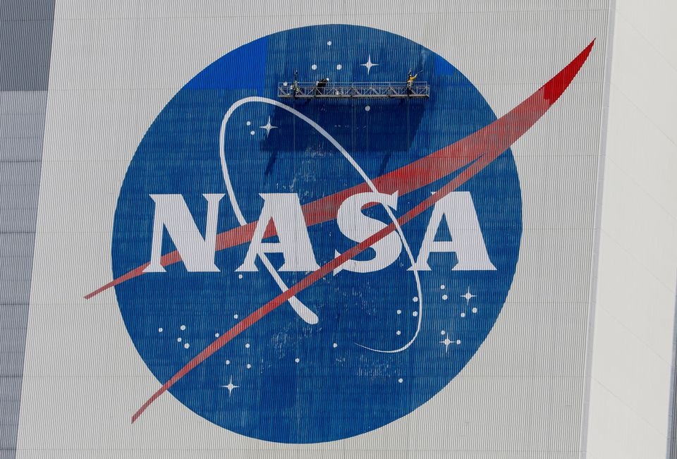 Workers pressure wash the logo of NASA on the Vehicle Assembly Building before SpaceX will send two NASA astronauts to the International Space Station aboard its Falcon 9 rocket, at the Kennedy Space Center in Cape Canaveral, Florida, U.S., May 19, 2020. REUTERS/Joe Skipper

