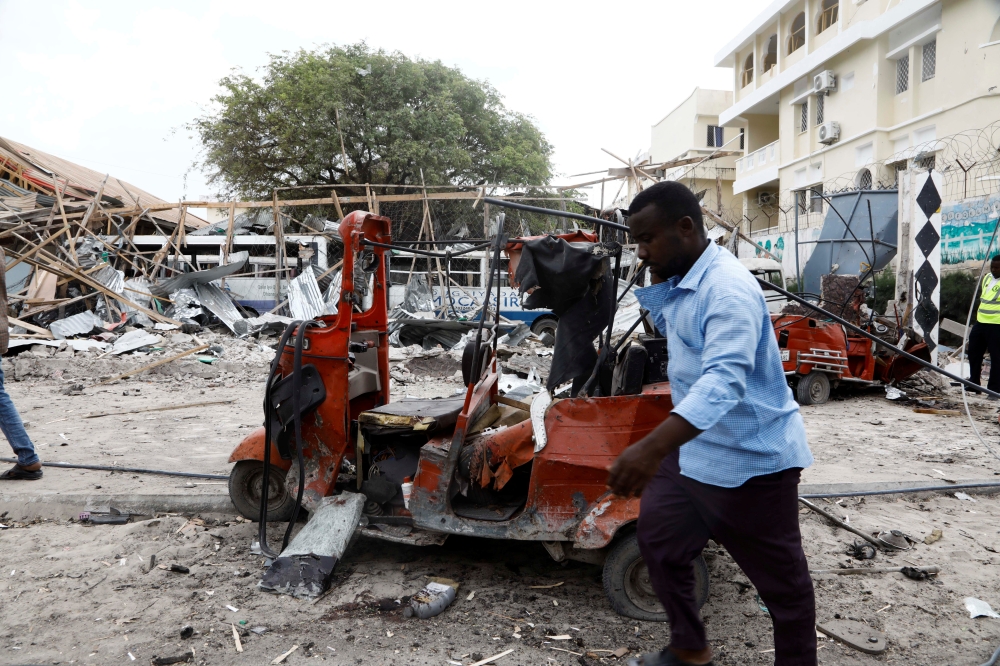 A civilian walks past the wreckages of vehicles and the debris of classrooms after a car exploded in a suicide attack near Mucassar primary and secondary school in Hodan district of Mogadishu, Somalia November 25, 2021. Reuters/Feisal Omar
 