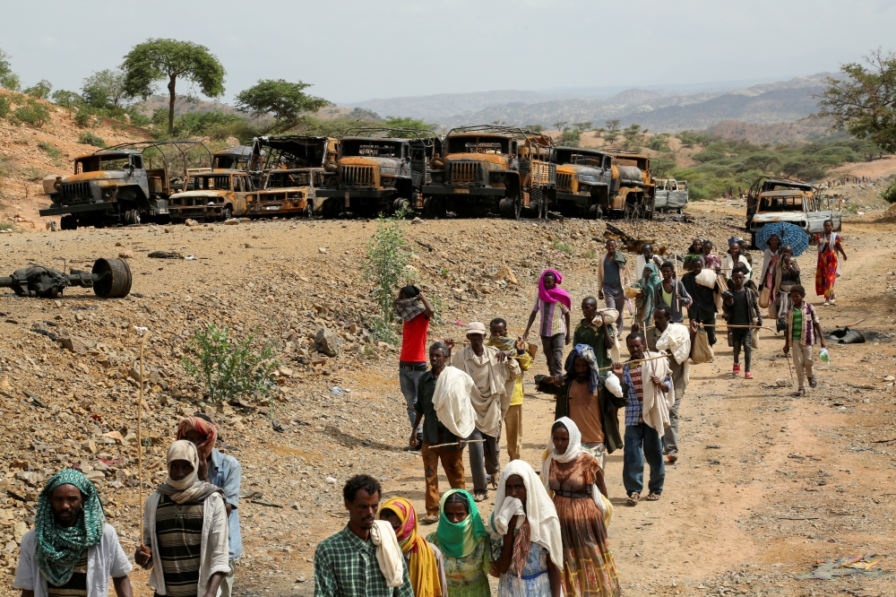 Villagers return from a market to Yechila town in south central Tigray walking past scores of burned vehicles, in Tigray, Ethiopia, July 10, 2021. REUTERS/Giulia Paravicini.