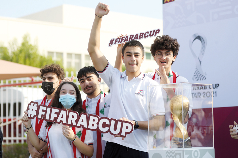 Fans pose with the FIFA Arab Cup Qatar 2021 trophy. 