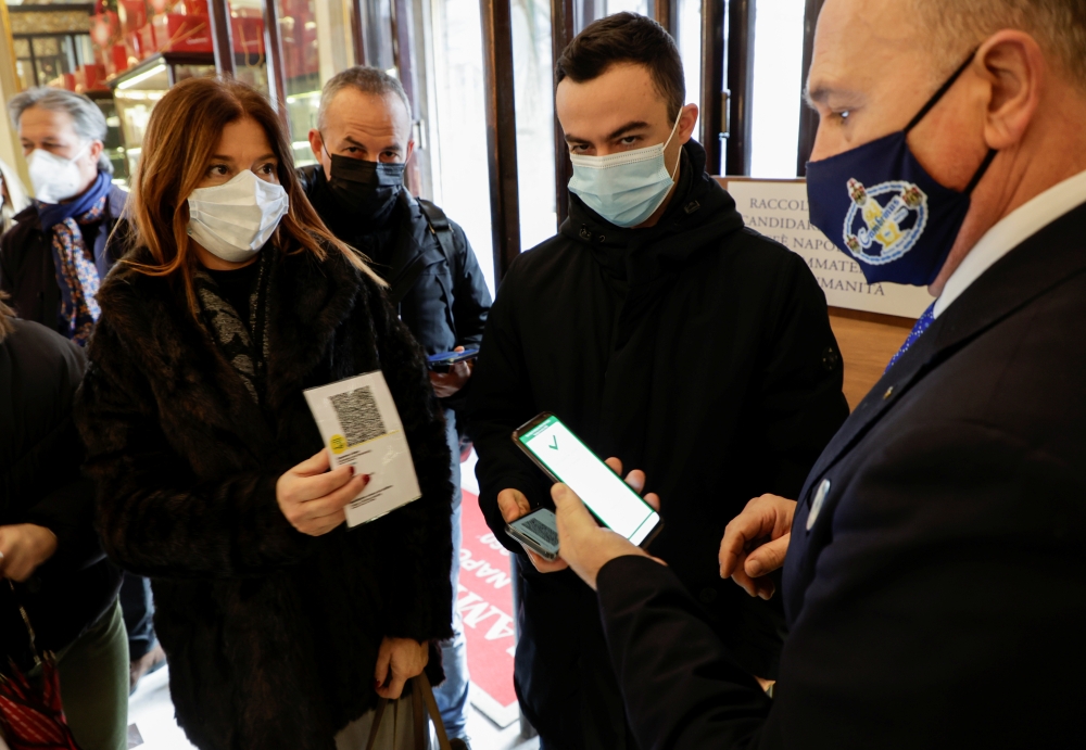 Customers have their coronavirus disease (COVID-19) health pass, known as a Green Pass, checked as they arrive at a bar the day the government restricts access of unvaccinated to indoor venues, in Naples, Italy December 6, 2021. REUTERS/Ciro de Luca