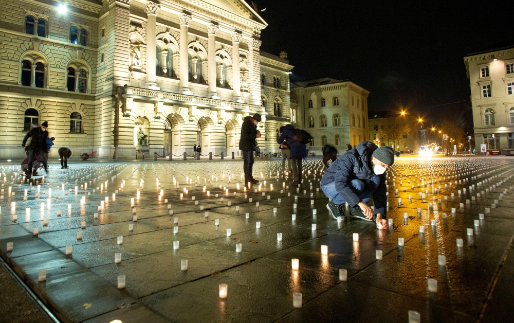 Volunteers light some of more than 11,000 candles, one for each victim of the coronavirus disease (COVID-19) pandemic in Switzerland, during a candlelight vigil in front of the seat of the Swiss federal parliament Bundeshaus in Bern, Switzerland December 7, 2021. Picture taken December 7, 2021. REUTERS/Arnd Wiegmann/File Photo
