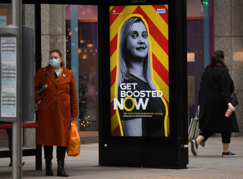 People walk past a government health campaign advertisement encouraging people to take a coronavirus disease (COVID-19) vaccine booster dose, at a bus stop in London, Britain, December 17, 2021. Reuters/Toby Melville