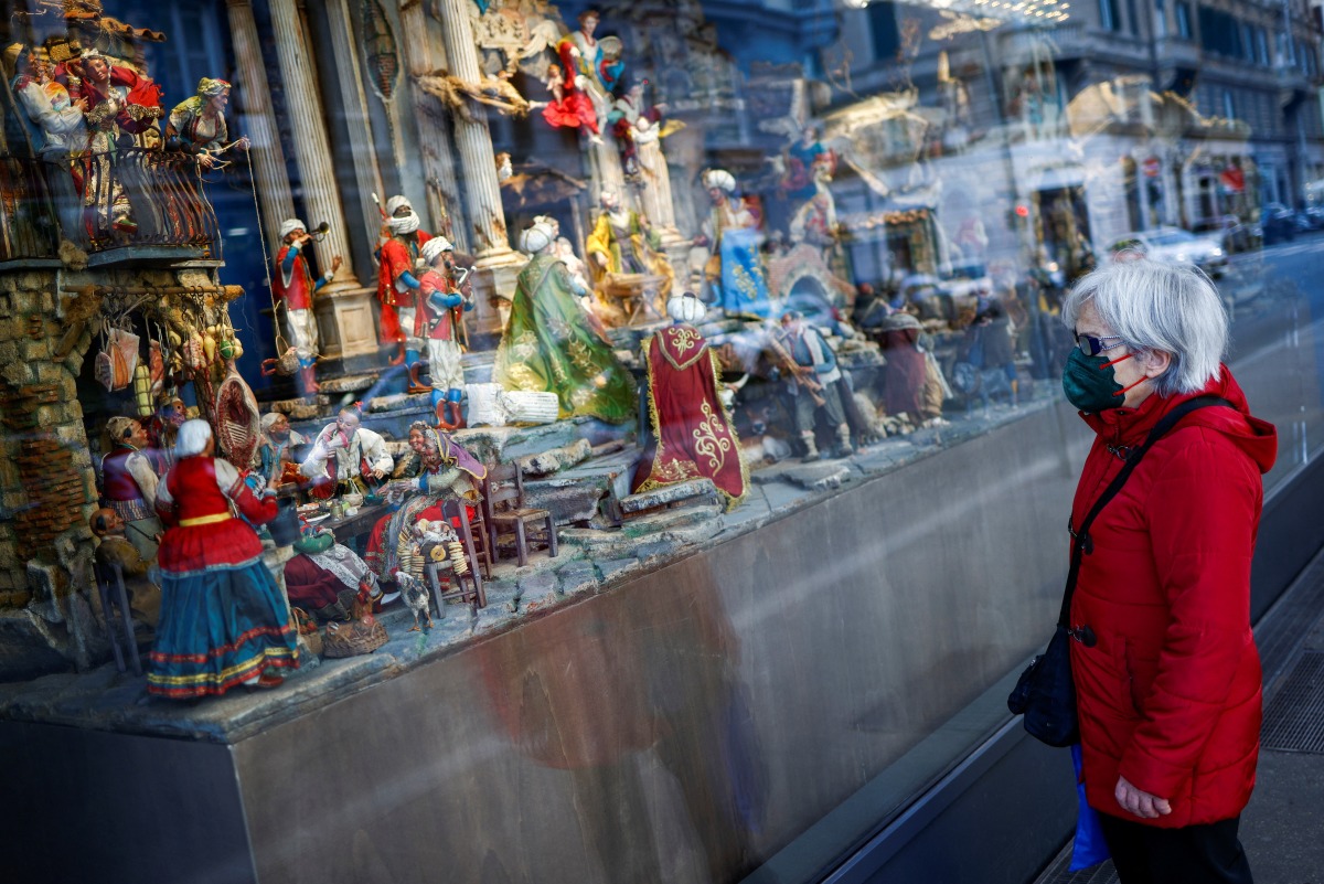 A woman wearing a face mask looks at a shop window with a nativity scene on display as coronavirus diseases (COVID-19) infections rise, in Rome, Italy, December 29, 2021. REUTERS/Guglielmo Mangiapane
