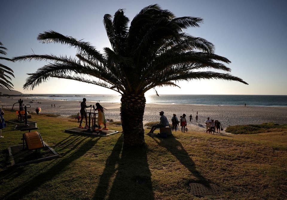Vistors take in the sunlight at Camps Bay beach as the city experiences a subdued Christmas season after months of lockdowns and worries about the spread of the coronavirus disease (COVID-19) in Cape Town, South Africa, December 23, 2021. REUTERS/Mike Hutchings/File Photo



