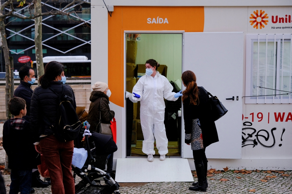A health worker talks to people while they wait to do tests for the coronavirus disease (COVID-19) on the day before Christmas eve in Campo Pequeno, Lisbon, Portugal, December 23, 2021. REUTERS/Pedro Nunes/File Photo