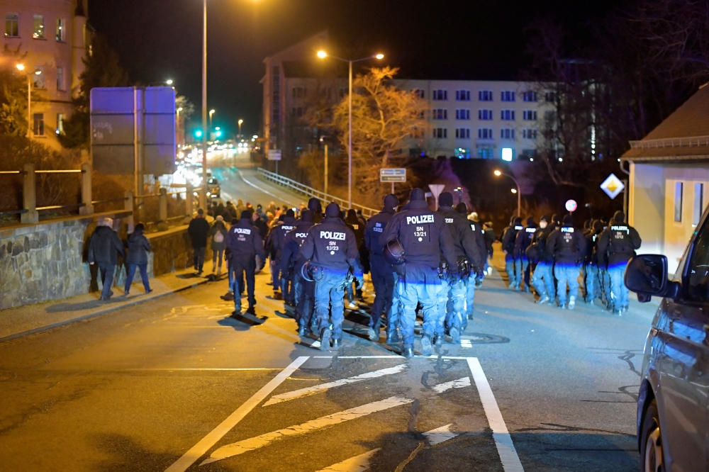 Police officers keep watch over a demonstration against government measures to curb the spread of the coronavirus disease (COVID-19) in Bautzen, Germany, January 3, 2022. Reuters/Matthias Rietschel