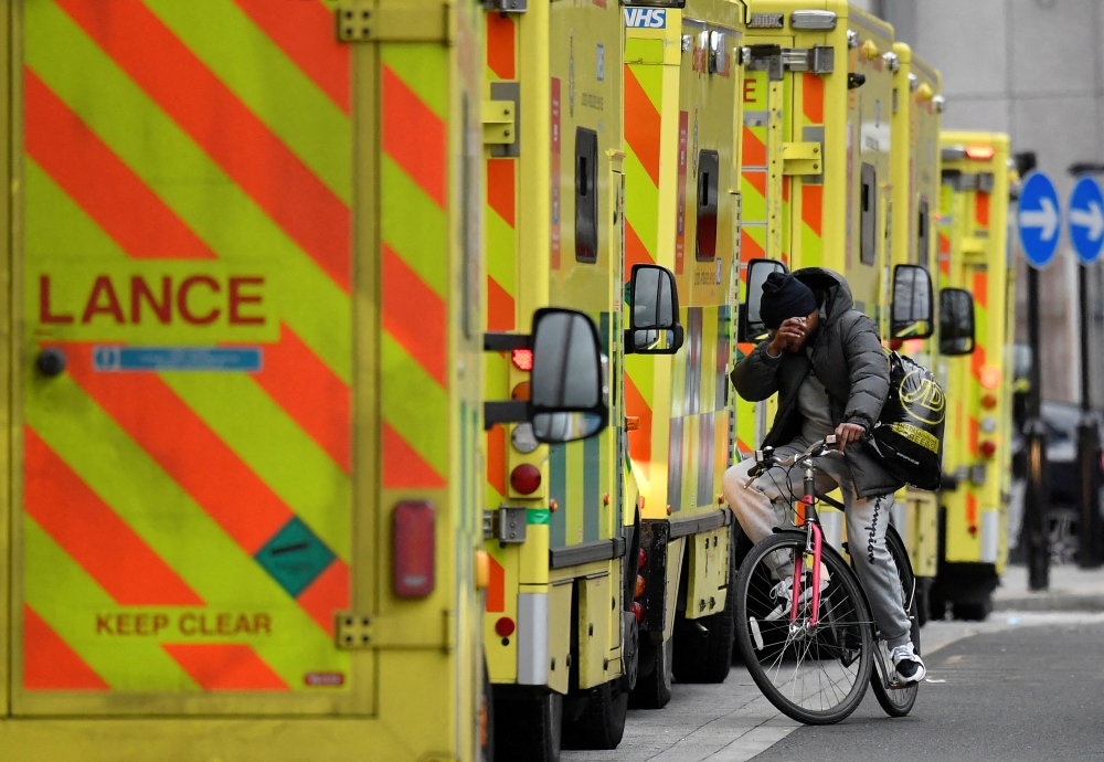 A man cycles between ambulances parked outside of the Royal London Hospital in London, Britain, January 7, 2022. Reuters/Toby Melville/File Photo