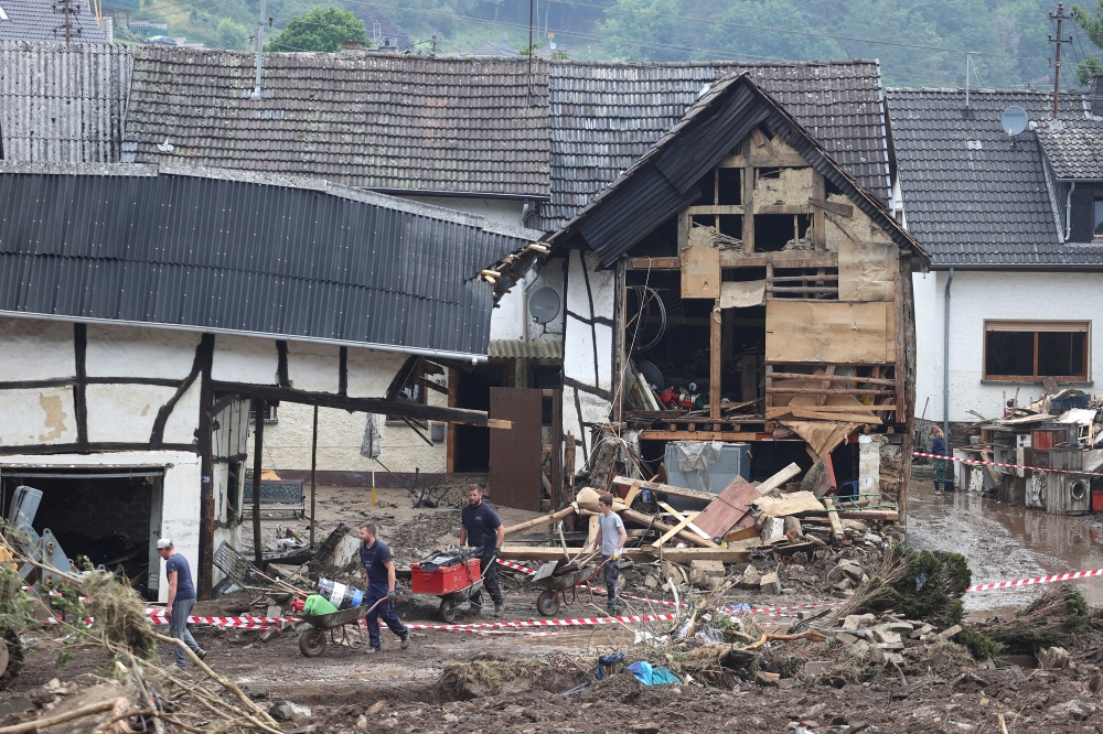 Residents remove rubble among the debris left over by the July 2021 extreme weather and lethal floods of the nearby Ahr river, in Schuld, Germany, July 17, 2021. REUTERS/Wolfgang Rattay/File Photo