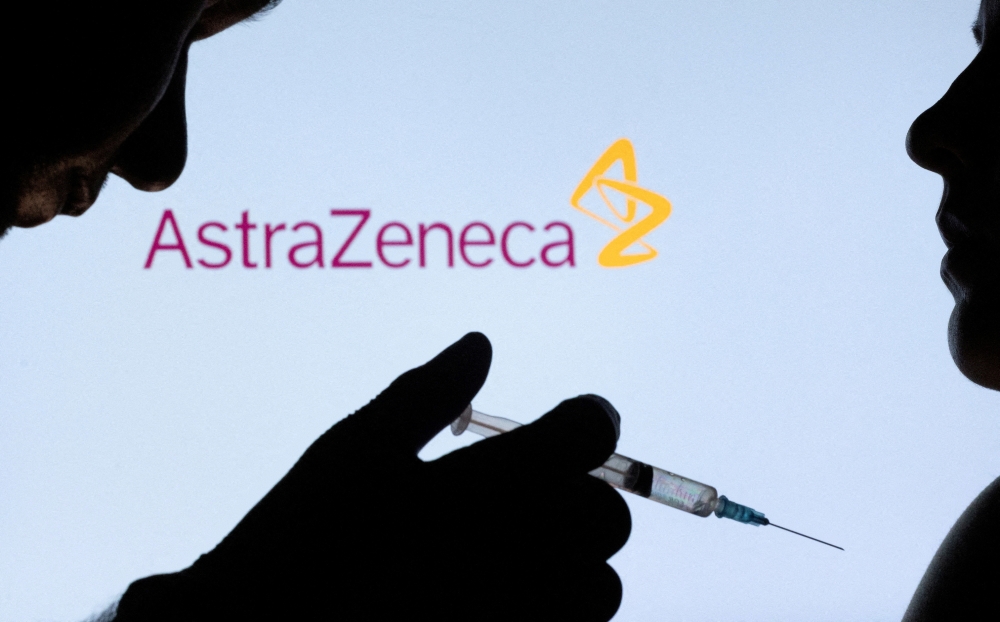 People pose with a needle in front of displayed AstraZeneca logo in this illustration taken December 11, 2021. REUTERS/Dado Ruvic/Illustration/File Photo