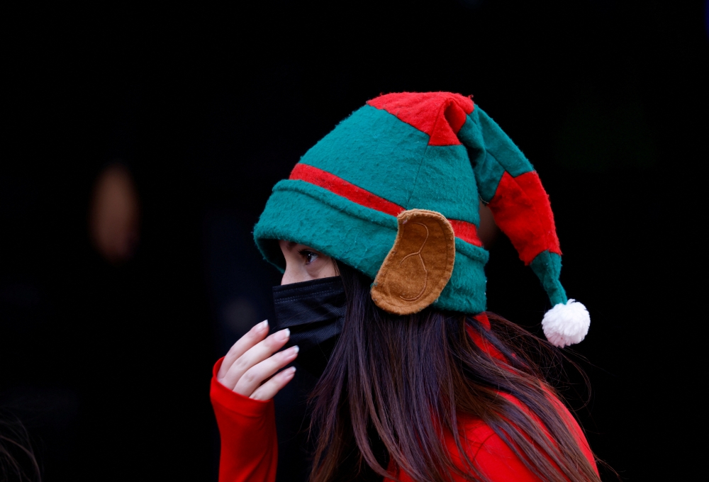  A woman dressed as an elf wears a face mask while handing out promotional leaflets in the street after mandatory mask wearing in indoor and outdoor spaces came into force because of the continuing coronavirus disease (COVID-19) pandemic, in Valletta, Malta December 11, 2021. REUTERS/Darrin Zammit Lupi/File Photo