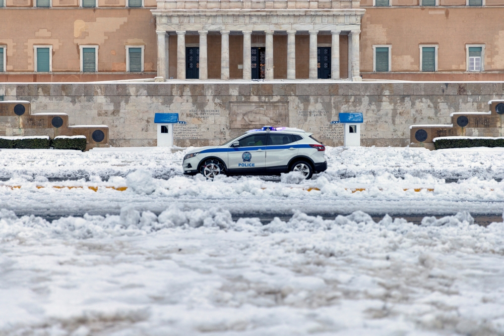 A police car drives past the Greek parliament building, following heavy snowfall in Athens, Greece, January 25, 2022. REUTERS/Alkis Konstantinidis