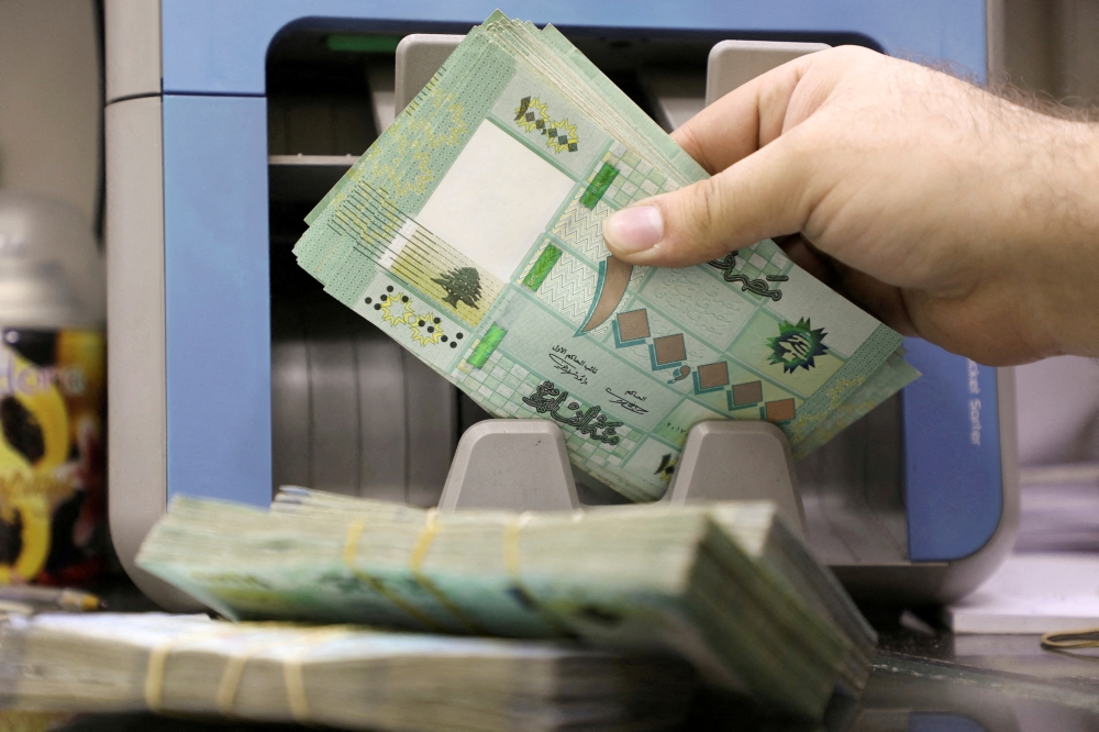 FILE PHOTO: A man counts Lebanese pound banknotes at a currency exchange shop in Beirut, Lebanon, January 5, 2022. Picture taken January 5, 2022. REUTERS/Mohamed Azakir