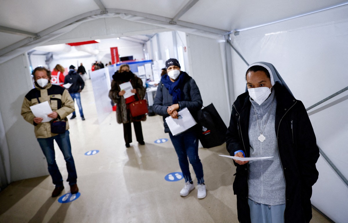 FILE PHOTO: People wait to get a dose of the vaccine against the coronavirus disease (COVID-19), on the day Italy brings in tougher rules for the unvaccinated, at a Red Cross vaccination centre by Termini main train station in Rome, Italy, January 10, 2022. REUTERS/Guglielmo Mangiapane//File Photo

