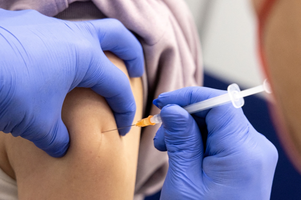 A woman gets a dose of Comirnaty, the Pfizer-BioNTech vaccine against the coronavirus disease (COVID-19), one day before the start of compulsory vaccination in Austria during the ongoing coronavirus disease (COVID-19) pandemic, at a vaccination centre in Salzburg, Austria, January 31, 2022. REUTERS/Lukas Barth/File Photo