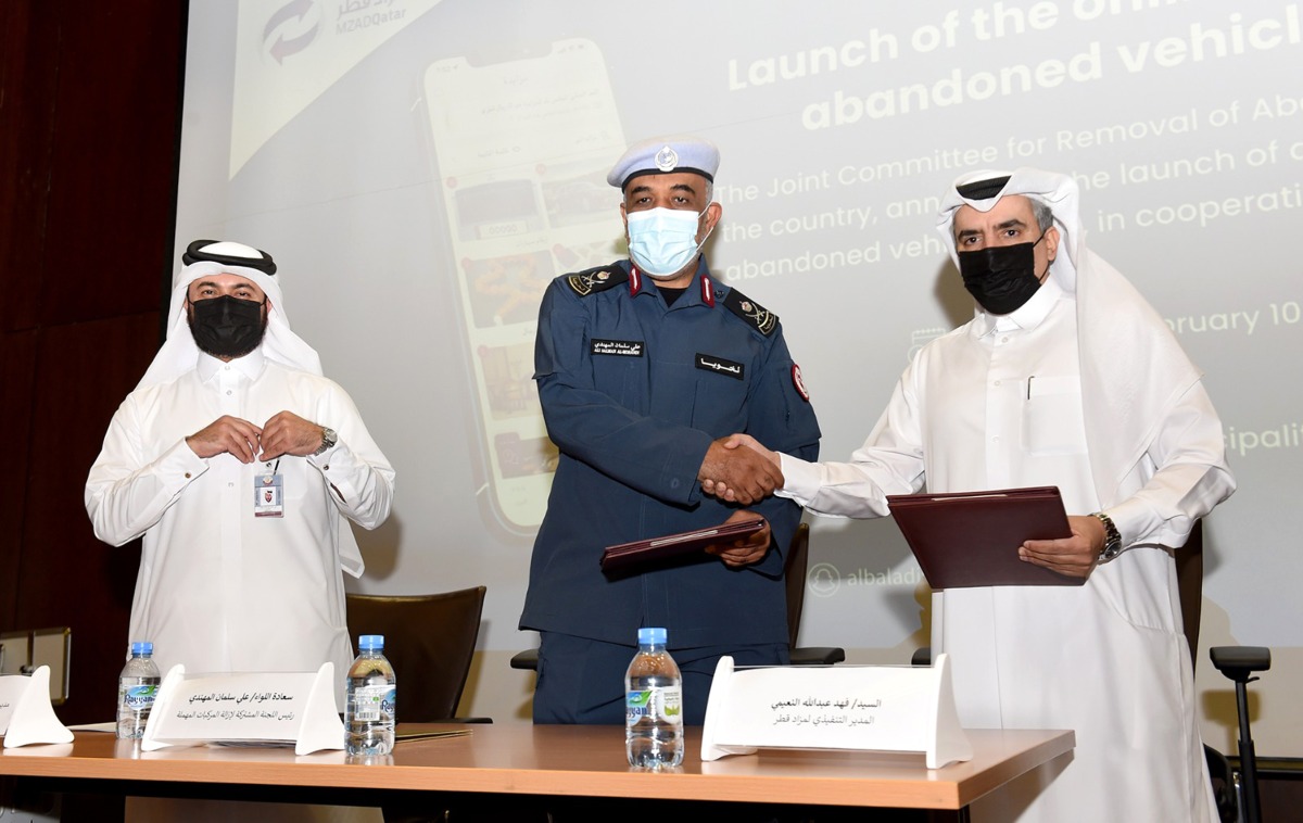 Chairman of Joint Committee for Removing Abandoned Vehicles Major General Ali Salman Al Mohannadi and Executive Director of Mzad Qatar Fahad Abdullah Al Nuaimi exchanging documents after signing the agreement.