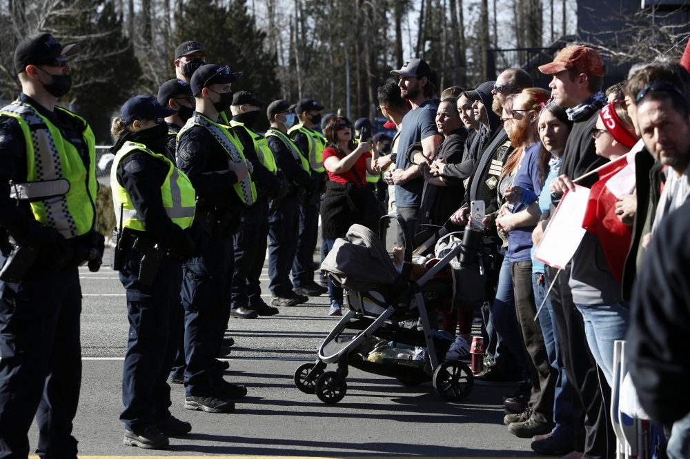 Police officers hold back a line of protesters as truckers and supporters continue to protest against the coronavirus disease (COVID-19) vaccine mandates, near the Canada and U.S. border crossing in Surrey, British Columbia, Canada, February 13, 2022. REUTERS/Jesse Winter
