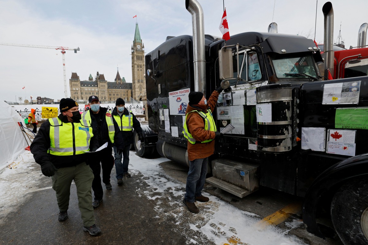 Police had out information sheets and speak to demonstrators as truckers and supporters continue to protest coronavirus disease (COVID-19) vaccine mandates, in Ottawa, Ontario, Canada, February 16, 2022. REUTERS/Blair Gable
