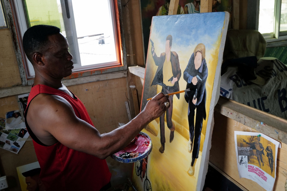 Ghanaian movie poster artist Daniel Anum Jasper, 54, works on a commissioned movie poster for a foreign client at his worksop in the Teshie area of Accra, Ghana February 11, 2022. REUTERS/Francis Kokoroko