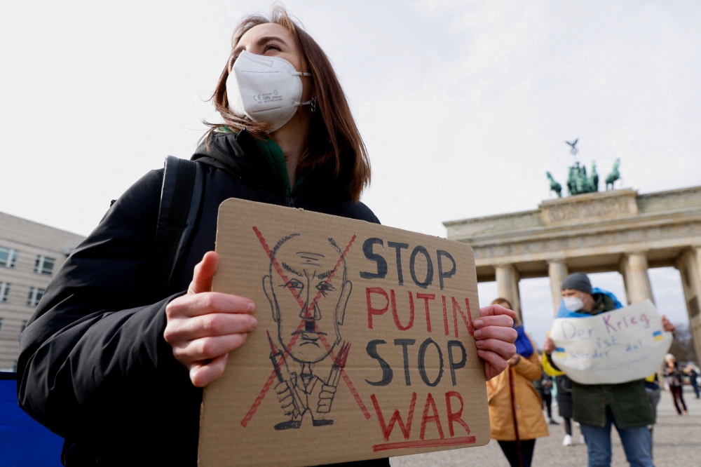 People hold signs as they demonstrate at Brandenburg Gate, after Russian President Vladimir Putin authorized a military operation in eastern Ukraine, in Berlin, Germany February 24, 2022. REUTERS/Michele Tantussi
