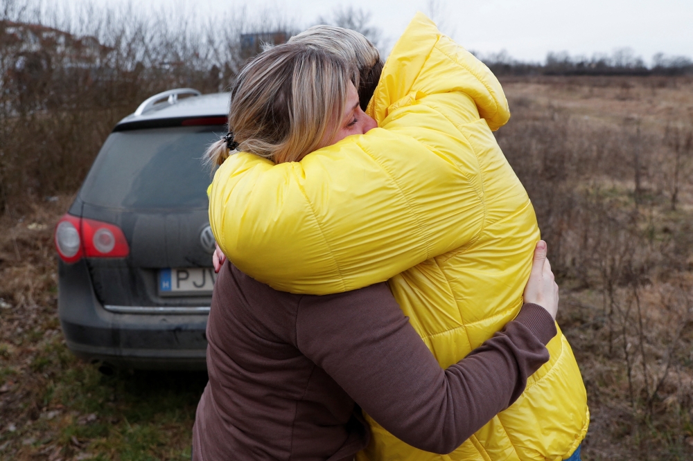 People fleeing from Ukraine embrace as they arrive in Hungary, after Russia launched a massive military operation against Ukraine, at a border crossing in Beregsurany, Hungary, February 26, 2022. REUTERS/Bernadett Szabo