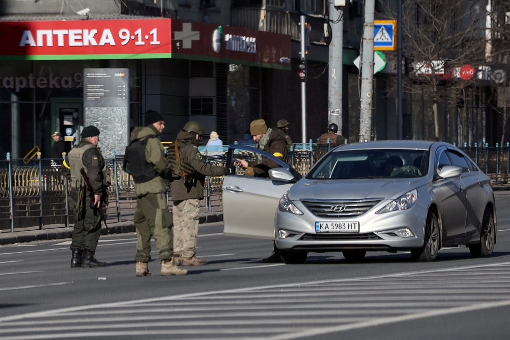 Locals stop a car at a checkpoint after Russia launched a massive military operation against Ukraine, in Kyiv, Ukraine February 26, 2022. REUTERS/Carlos Barria