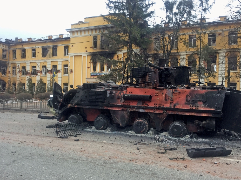A destroyed Ukrainian armoured personnel carrier vehicle is seen in front of a school which, according to local residents, was on fire after shelling, as Russia's invasion of Ukraine continues, in Kharkiv, Ukraine February 28, 2022. Reuters/Vitaliy Gnidyi