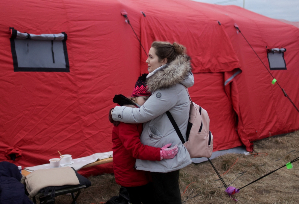 A woman hugs a child as they wait for transport after fleeing the Russian invasion of Ukraine, at a border crossing in Vysne Nemecke, Slovakia. Reuters/Lukasz Glowala