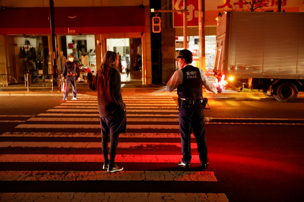 A police talks with a local resident on the street during an electric stoppage at the area after an earthquake in Tokyo, Japan March 17, 2022. REUTERS/Issei Kato