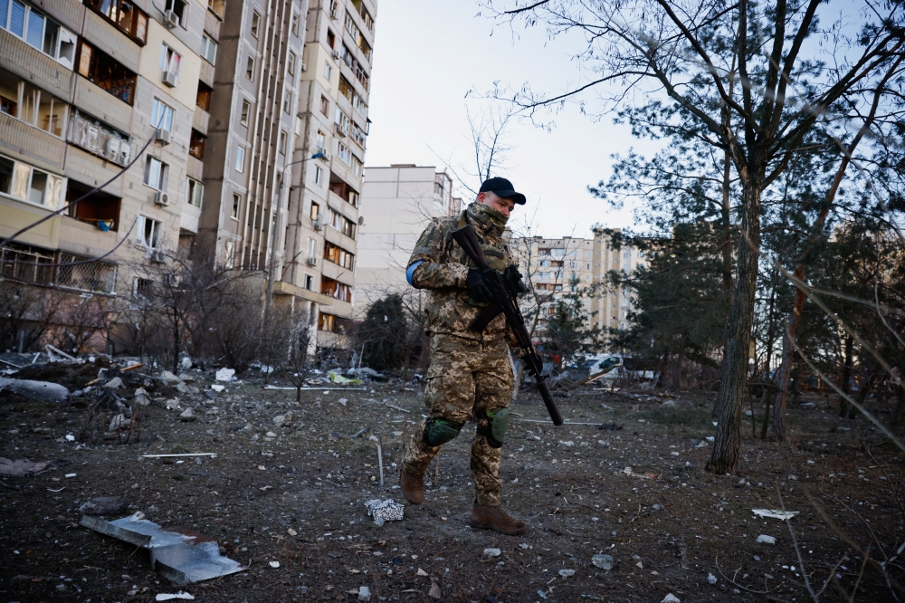 A member of the Ukrainian military surveys an area next to a residential building that was hit by an intercepted missile, as Russia's invasion of Ukraine continues, in Kyiv, Ukraine March 17, 2022. REUTERS/Thomas Peter