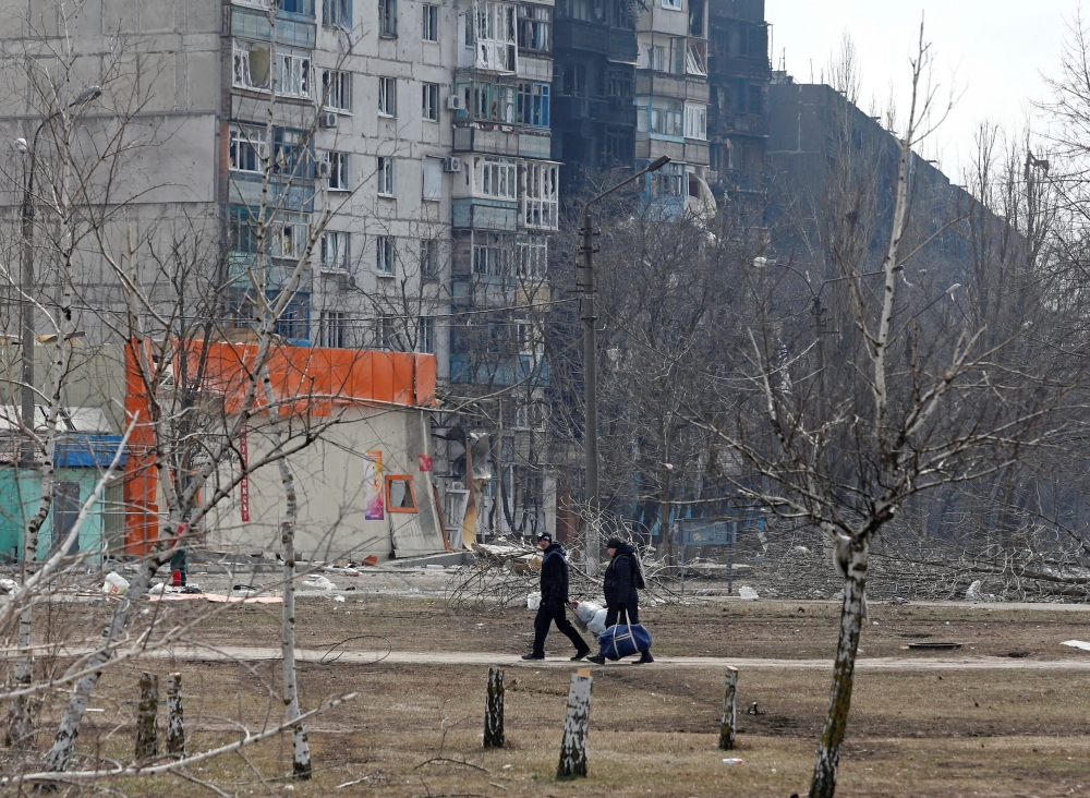Local residents walk near a residential building which was damaged during Ukraine-Russia conflict in the besieged southern port city of Mariupol, Ukraine March 18, 2022. REUTERS/Alexander Ermochenko