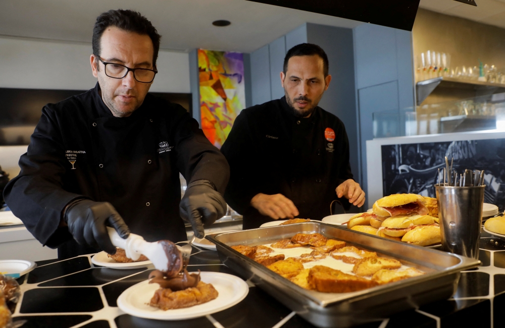 Spanish chef Ciriaco Vicente, 47, and his chef prepares sandwiches and sweets for Ukrainian refugees who come to eat at his restaurant on the beach in Valencia, Spain, March 28, 2022. Picture taken March 28, 2022. REUTERS/Eva Manez