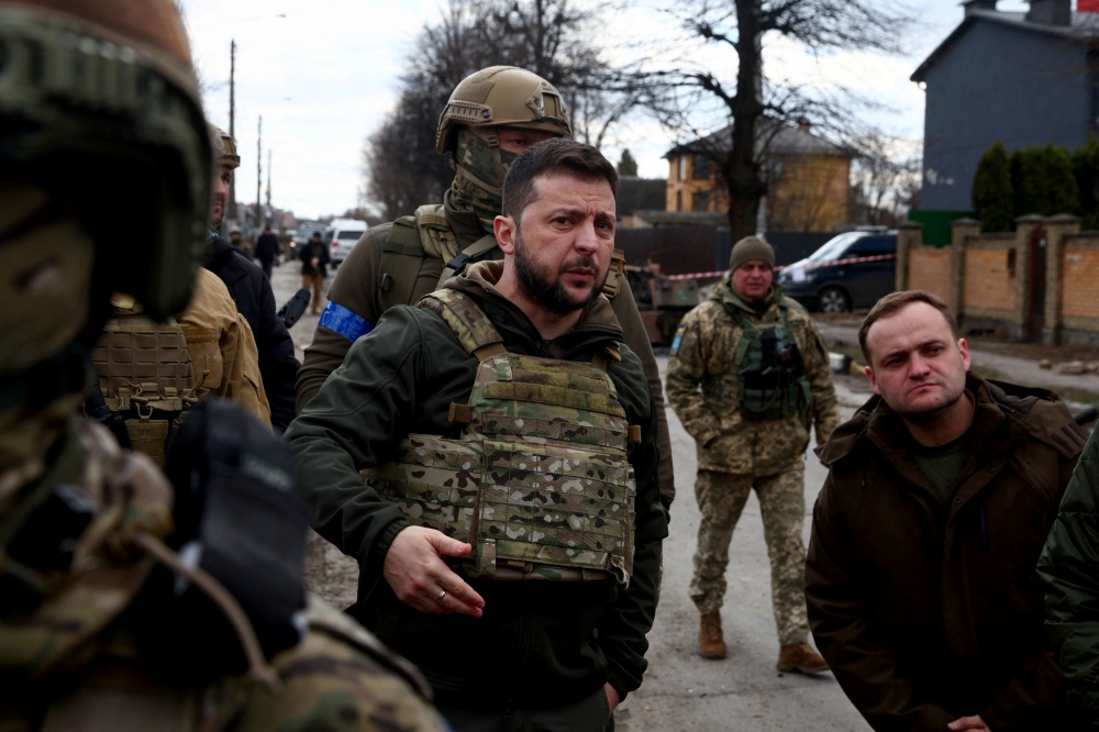 Ukraine's President Volodymyr Zelenskiy gestures as he is surrounded by Ukrainian servicemen as Russia's invasion of Ukraine continues, in Bucha, outside Kyiv, Ukraine, April 4, 2022. REUTERS/Marko Djurica