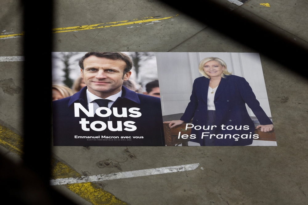 Official campaign posters of French President and centrist LREM party candidate for re-election Emmanuel Macron and Marine Le Pen, leader of French far-right National Rally (Rassemblement National) party, are displayed at France Affichage Plus dispatch hub in Mitry-Mory, outside Paris, France, France, April 13, 2022. Reuters/Benoit Tessier