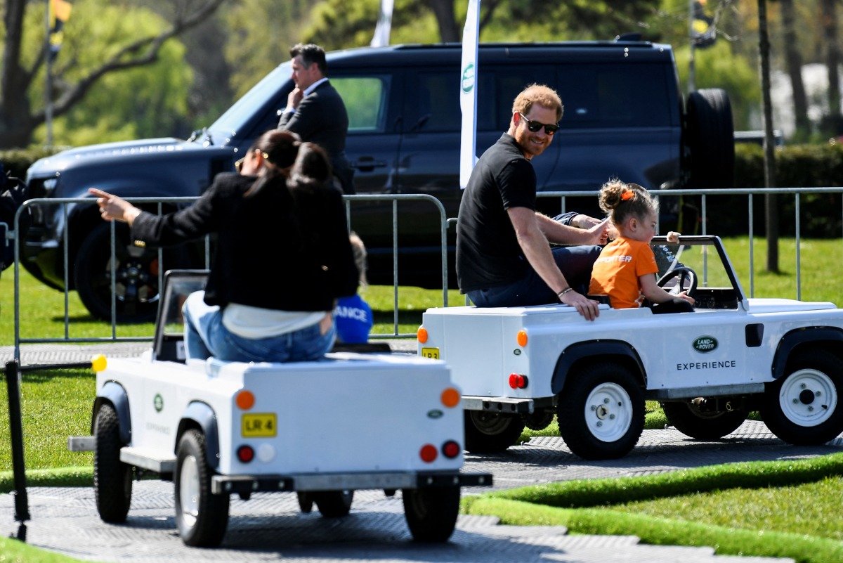 Britain's Prince Harry and Meghan, Duchess of Sussex, ride mini Land Rover model vehicles with children as they attend the Land Rover Driving Challenge of the Invictus Games in The Hague, Netherlands April 16, 2022. REUTERS/Piroschka Van De Wouw
