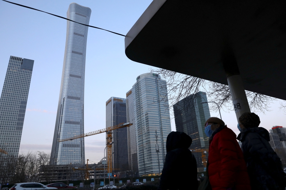 People wait at a bus stop in Beijing's Central Business District (CBD), China January 16, 2022. Picture taken January 16, 2022. REUTERS/Tingshu Wang/File Photo