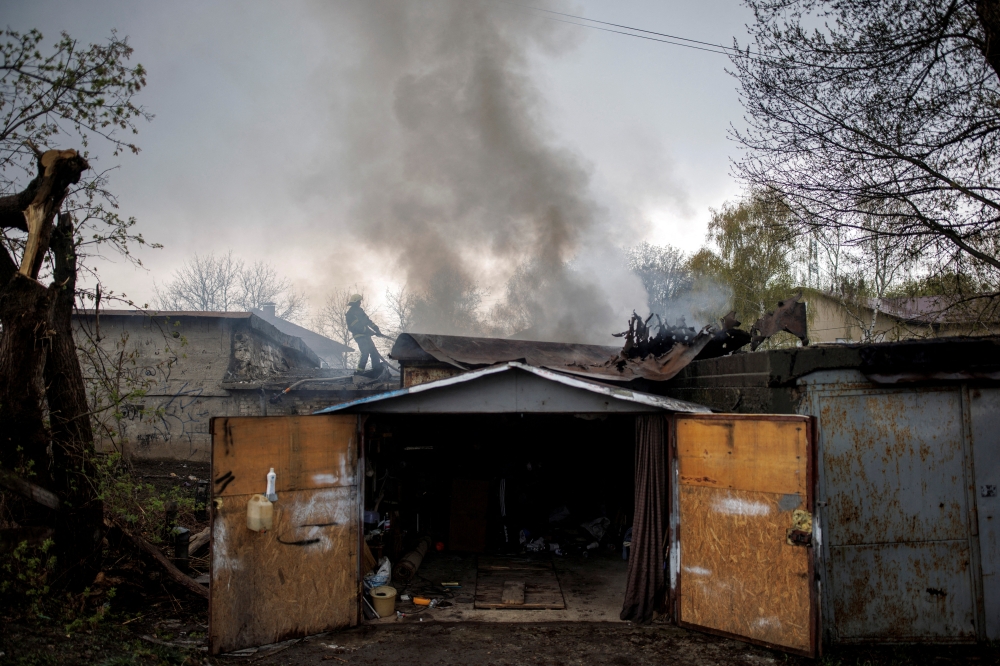 A firefighter tries to extinguish a fire burning at a garage, following Russian shelling, amid Russia's attack on Ukraine, in Kharkiv, Ukraine, April 18, 2022. REUTERS/Alkis Konstantinidis/File Photo