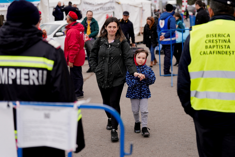 A woman and child walk after crossing from Ukraine to Romania, amid the Russian invasion of Ukraine, at the border crossing point in Siret, Romania April 16, 2022. REUTERS/Fedja Grulovic/File Photo