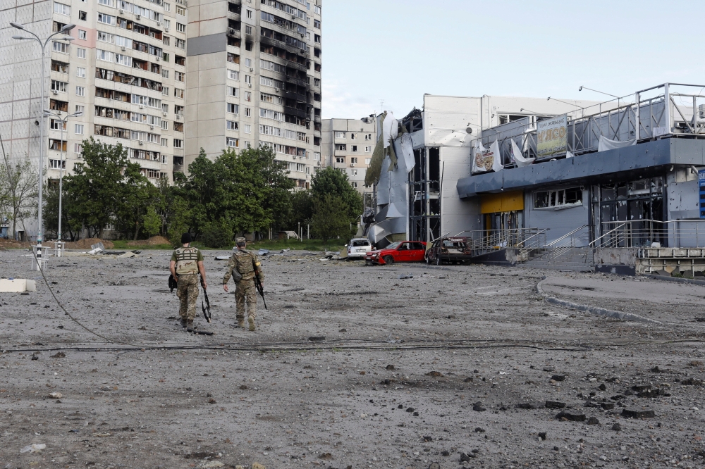 Ukrainian servicemen walk at a damaged area, as Russia's attack on Ukraine continues, in Kharkiv, Ukraine, May 14, 2022. REUTERS/Ricardo Moraes