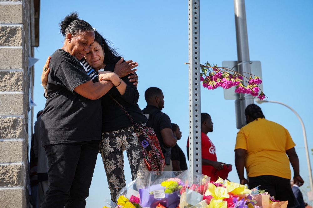 Women look at a memorial for victims near the scene of a shooting at a TOPS supermarket in Buffalo, New York, U.S. May 15, 2022. REUTERS/Brendan McDermid
