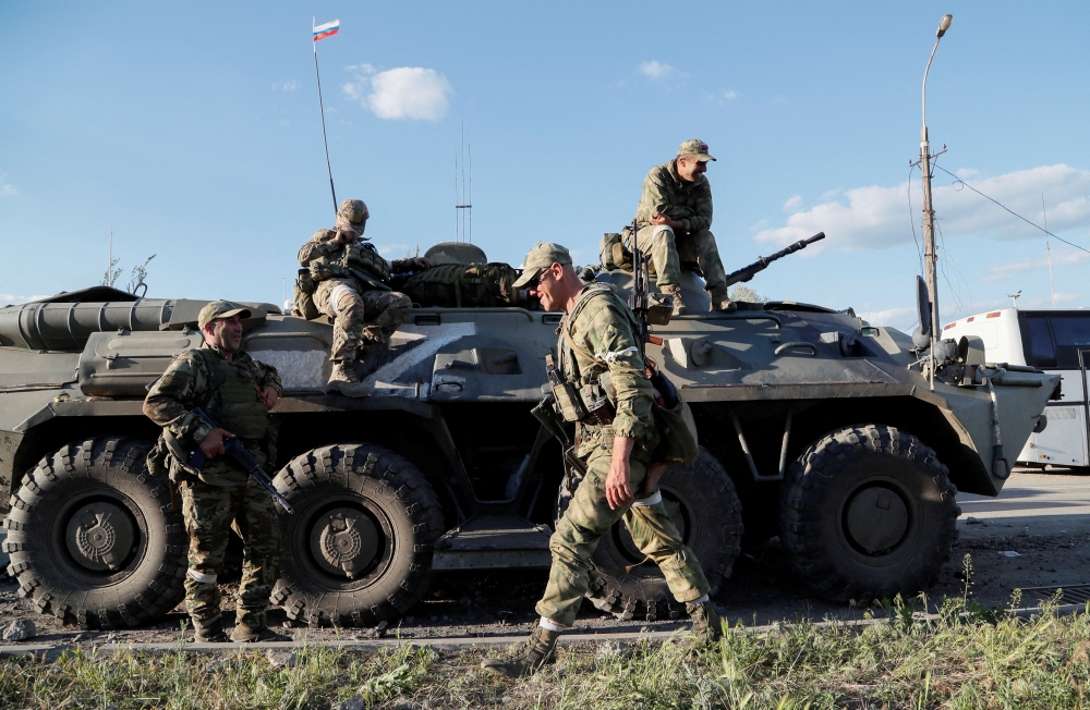 FILE PHOTO: Service members of pro-Russian troops wait before the expected evacuation of wounded Ukrainian soldiers from the besieged Azovstal steel mill in the course of Ukraine-Russia conflict in Mariupol, Ukraine May 16, 2022. REUTERS/Alexander Ermochenko