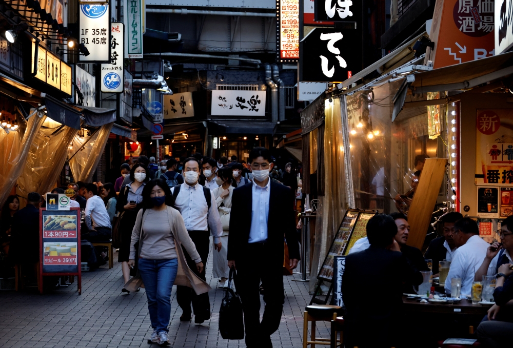 Passersby wearing protective face masks, following an outbreak of the coronavirus disease (COVID-19), walk on the steet at an izakaya pub alley in Tokyo, Japan June 9, 2022. REUTERS/Issei Kato